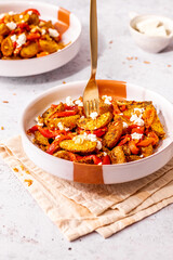 Plate with baby potatoes, roasted peppers, and crumbled feta cheese vegetarian quick lunch recipe on a table with hard light, and golden fork