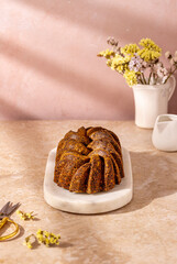 Hard shadows on the cake loaf standing on the oval marble tray with pastels colors and minimal set up