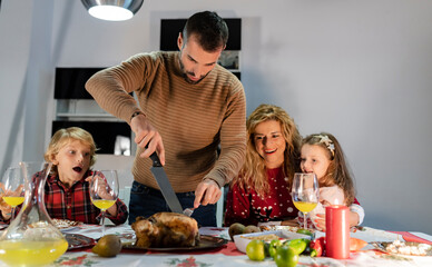 Obraz na płótnie Canvas family having christmas dinner at home. dad carves the turkey. - focus on man -