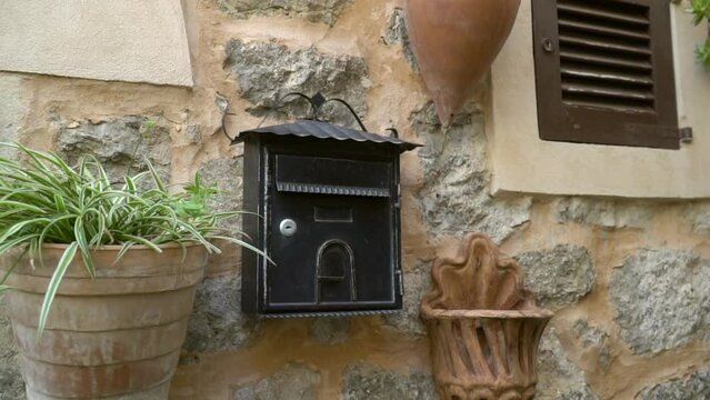 Metal delivering post mailbox on the wall of stones. Vintage black postmail on antique building. Old metal mailbox. Waiting for a letter. 