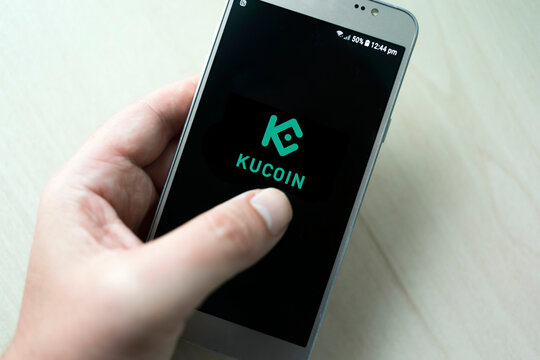 Gijon, Spain, 06-10-2022. Mobile phone app and Kucoin logo. App to invest or exchange Kucoin currency. Kucoin app. Kucoin is the platform for buying and selling cryptocurrencies