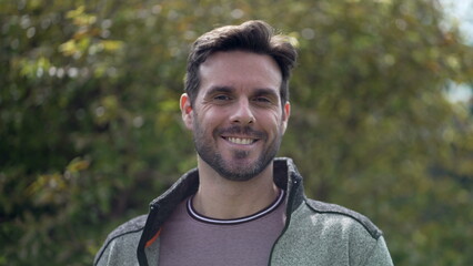 Happy handsome man smiling at camera. Portrait face closeup standing outdoors. 30s male person smiling