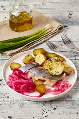 Herring with baked potato, onions and pickled cucumber