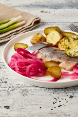 Herring with baked potato, onions and pickled cucumber, closeup