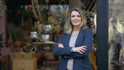 Businesswoman standing in front of small business store crossing arms smiling at camera. Portrait...