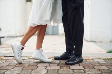 Close up view of legs on the ground. Beautiful bride with his fiance is celebrating wedding outdoors