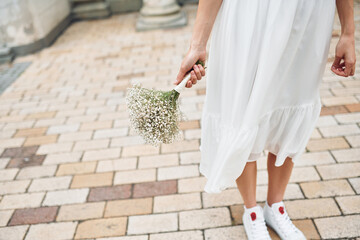 Particle view. With flowers in the hands. Bride in dress is outdoors before her wedding begins