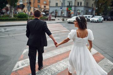 On the crosswalk. Beautiful bride with his fiance is celebrating wedding outdoors
