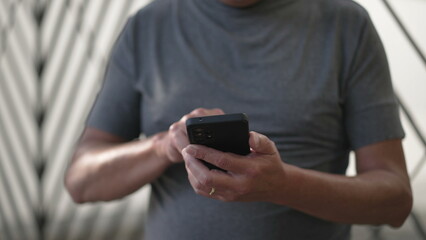 Person using cellphone standing outdoors in city street sidewalk. Closeup hands holding smartphone device texting message