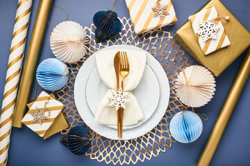 Christmas festive table setting with white plates and gold cutlery. Flatlay, in blue and gold colors