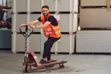 Fototapeta na wymiar Riding the platform trolley. Storage worker is in the warehouse with bunch of products
