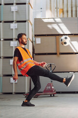 Playing soccer. Storage worker is in the warehouse with bunch of products