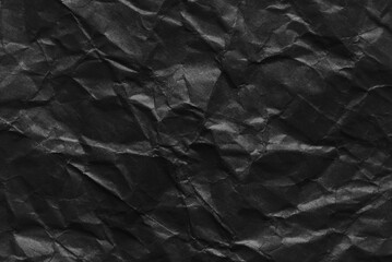 Black paper, a sheet of wrinkled black color paper texture as background
