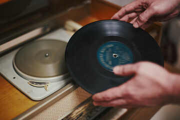 Vinyl record, spinning on turntable, Vintage record player with radio 60's. Mens hands putting...