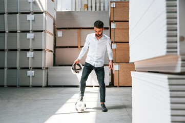 Taking a break, playing with soccer ball. Storage worker is in the warehouse with bunch of products