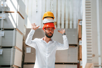Having fun with hard hats. Storage worker is in the warehouse with bunch of products