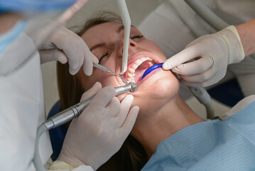 Woman having dental procedure in clinic. Concept of dentistry and orthodontic treatment.Close up of dentist hand using dental forceps while putting orthodontic braces on female patient teeth. 