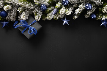 Christmas winter banner with gift, fir branches, blue navy balls on black background. Xmas greeting...