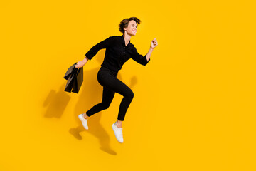 Fototapeta na wymiar Photo of pretty charming lady wear black shirt jumping high running fast empty space isolated yellow color background