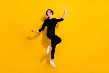 Fototapeta na wymiar Photo of sweet adorable lady wear black shirt jumping high empty space isolated yellow color background