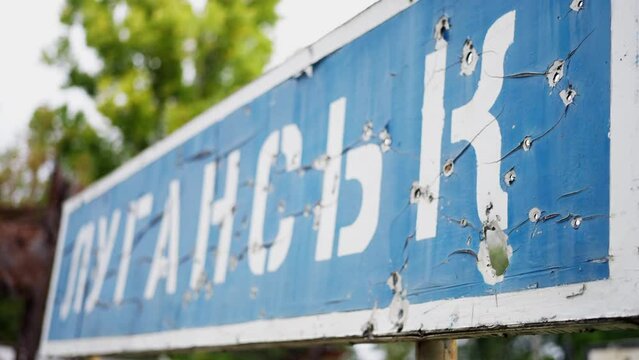War in Ukraine, city name sign in bullet holes, Lugansk. close-up