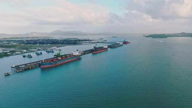 Aerial high angle drone footage of bulk carrier cargo ships docked at Gladstone coal terminal in Central Queensland, Australia. Gladstone operates one of Australia's largest coal export terminals.