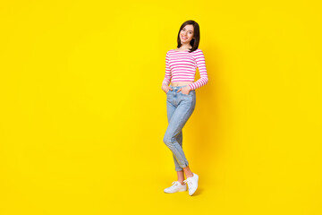 Fototapeta na wymiar Full length photo of lovely young woman shopping try on new jeans defile dressed stylish striped outfit isolated on yellow color background