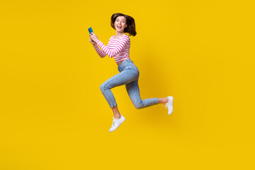 Fototapeta na wymiar Full length photo of gorgeous lovely girl brunette bob hair dressed striped top jumping hold phone isolated on yellow color background