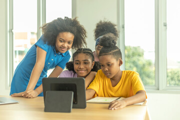 A group of young African kids with their sister use a tablet to communicate with friends. Happy kids use computer at home to socialize with other kids. Technology for education