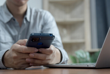 man hands using mobile phone and computer at office desk.Business working online communications e-commerce internet services at home office concept.