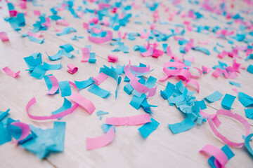 Pink and blue confetti scattered on the floor. Colored paper on laminate. Holiday concept. Close-up