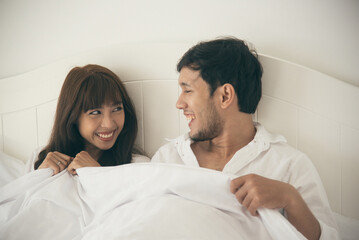 Obraz na płótnie Canvas Asian couple laying and talking in bed together. Happy young lovely couple.