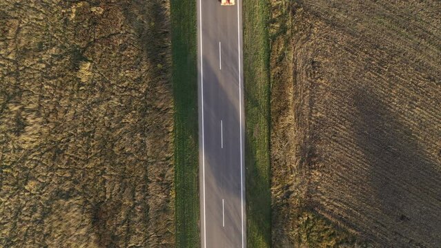 Bird's eye view of semi truck carrying bulldozer on highway, top down drone pov