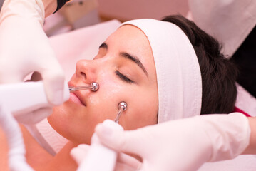 Obraz na płótnie Canvas Young woman getting facial mask skin treatment in professional beauty salon