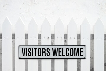 Visitors Welcome sign on the fence against white wall