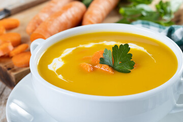 Carrot soup with cream and parsley on wooden table. Close up