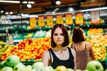 Woman in a supermarket at the shelf for fruits shopping apple