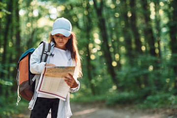 Using the map. Girl is in the forest at summer day time discovering new places