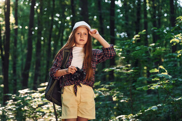 Young photographer with camera. Girl is in the forest at summer day time discovering new places