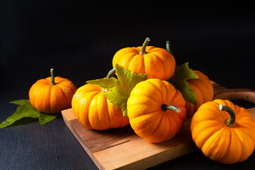 Food background concept Organic mini pumpkins on wooden board on black background with copy space