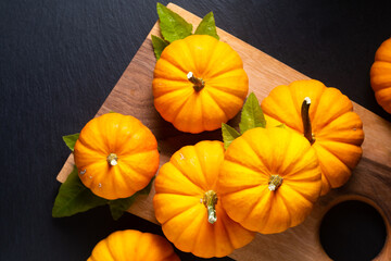 Food background concept Organic mini pumpkins on wooden board on black background with copy space