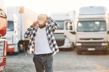 Wearing the cap. Young truck driver is with his vehicle at daytime