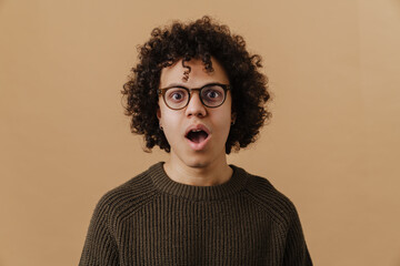Fototapeta na wymiar Young handsome curly shocked boy in glasses and sweater