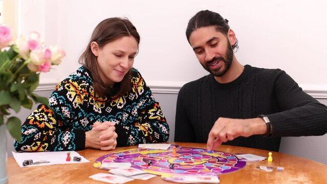 South Asian man and young white woman playing board game