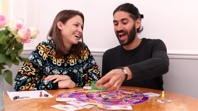 South Asian man and young white woman playing board game and laughing