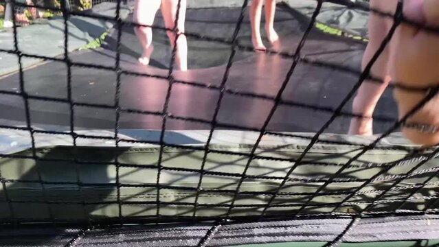 Backyard trampoline with kids having fun jumping and bouncing