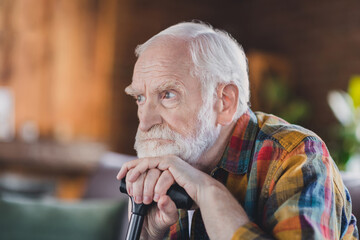 Photo of angry moody man pensioner wear sitting sofa chin arms walking cane indoors house room
