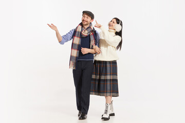 Portrait of stylish young people, man and woman in winter clothes cheerfully talking over white background