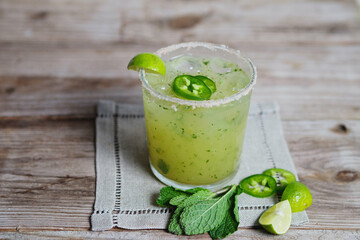 Glass of Mint margarita with some lime , green chilly and lemon.