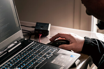 Close up of man's hand using wireless mouse and laptop computer with blue backlit keyboard